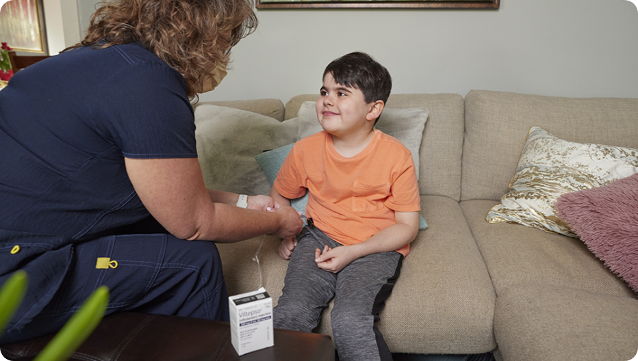 Close-up of Mason, a VILTEPSO patient, smiling with bookshelves behind him.