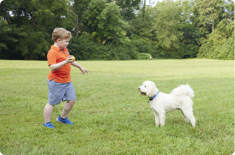 Jordan, a VILTEPSO patient, sitting outdoors beside a large brown dog.